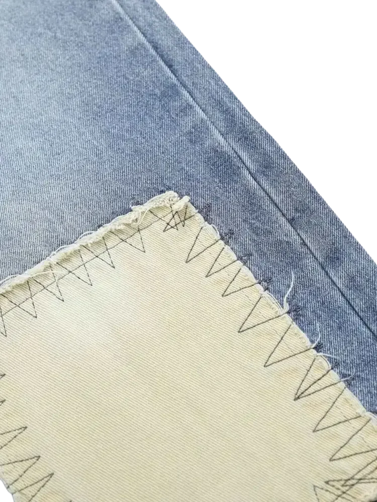 Pale yellow vintage patchwork wide fabric patch with black zigzag stitching on blue denim