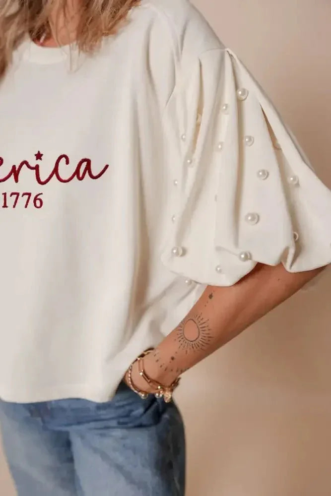AMERICA EST 1776 Embroidered Pearl Beaded Sleeve T Shirt - Update AvenueT-ShirtsTrendsi1001008044689171001008044689177ece6985 - 2c0f - 4027 - 982a - 6851432a333e - Max - OriginWhite