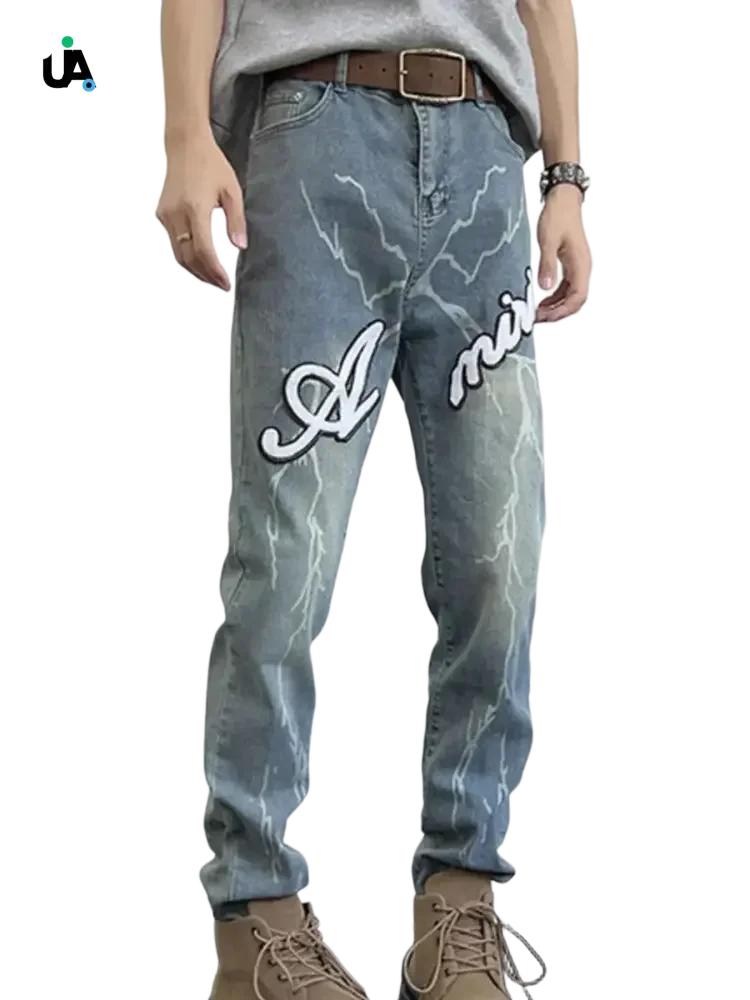 Men’s light wash blue slim fit jeans with lightning bolt graphics and Amiri embroidery