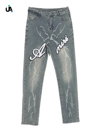 Light-wash blue denim jeans with white lightning bolt designs and Amiri branding, size slim fit, plus fit jeans