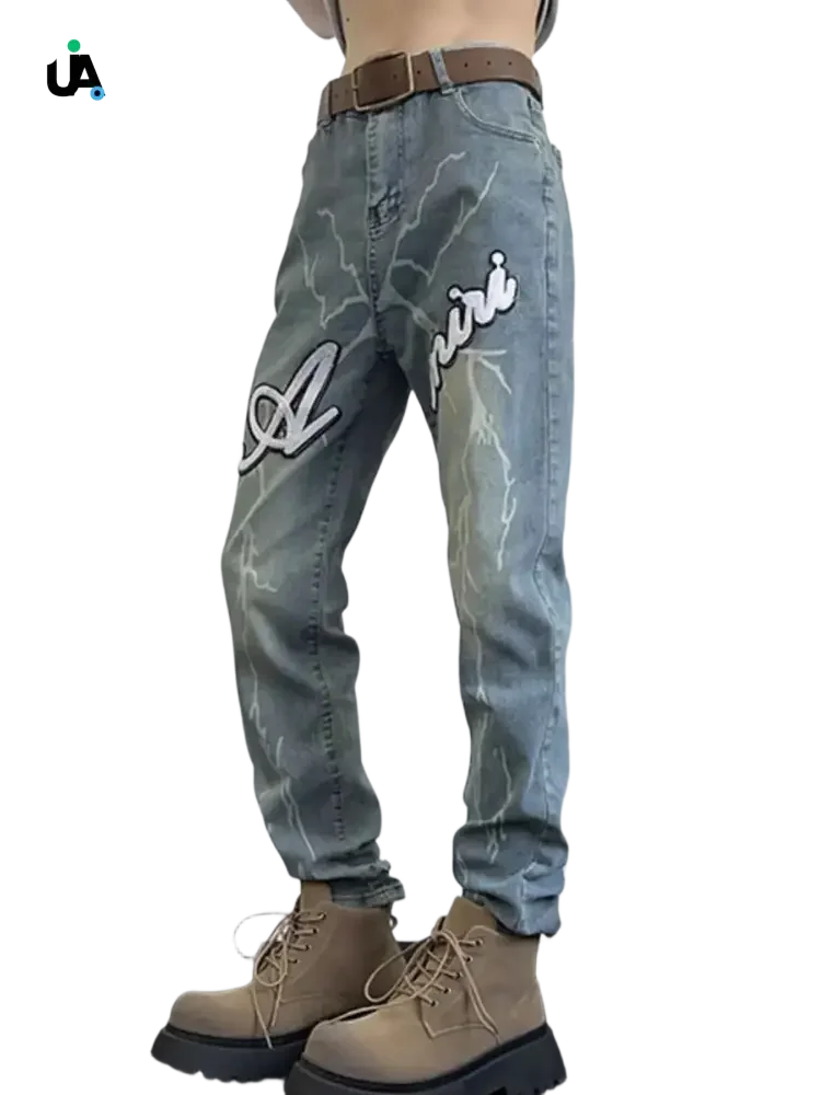 Light-wash denim jeans with white lightning bolt designs and Amiri branding, size slim fit plus